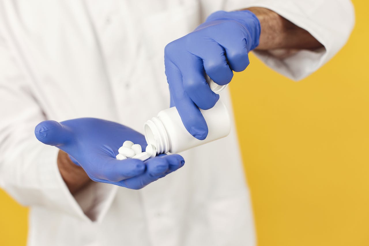 Gloved hand taking pills from a bottle