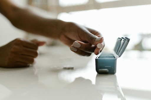 Woman filling pill box to practice medication adherence