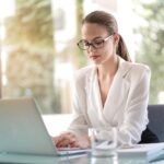 Woman in white jacket on a laptop learning how to use pharmacy software