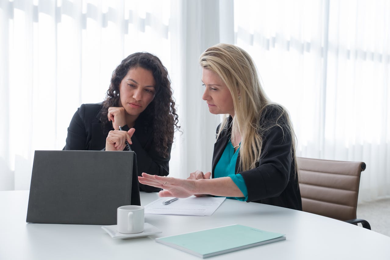 A woman demonstrating pharmacy software on a tablet to a pharmacist in a one-on-one meeting