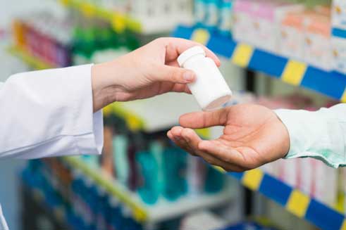 One person’s hand placing a white bottle in another person’s hand.
