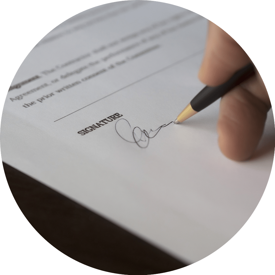 A person signing a document with a black pen.