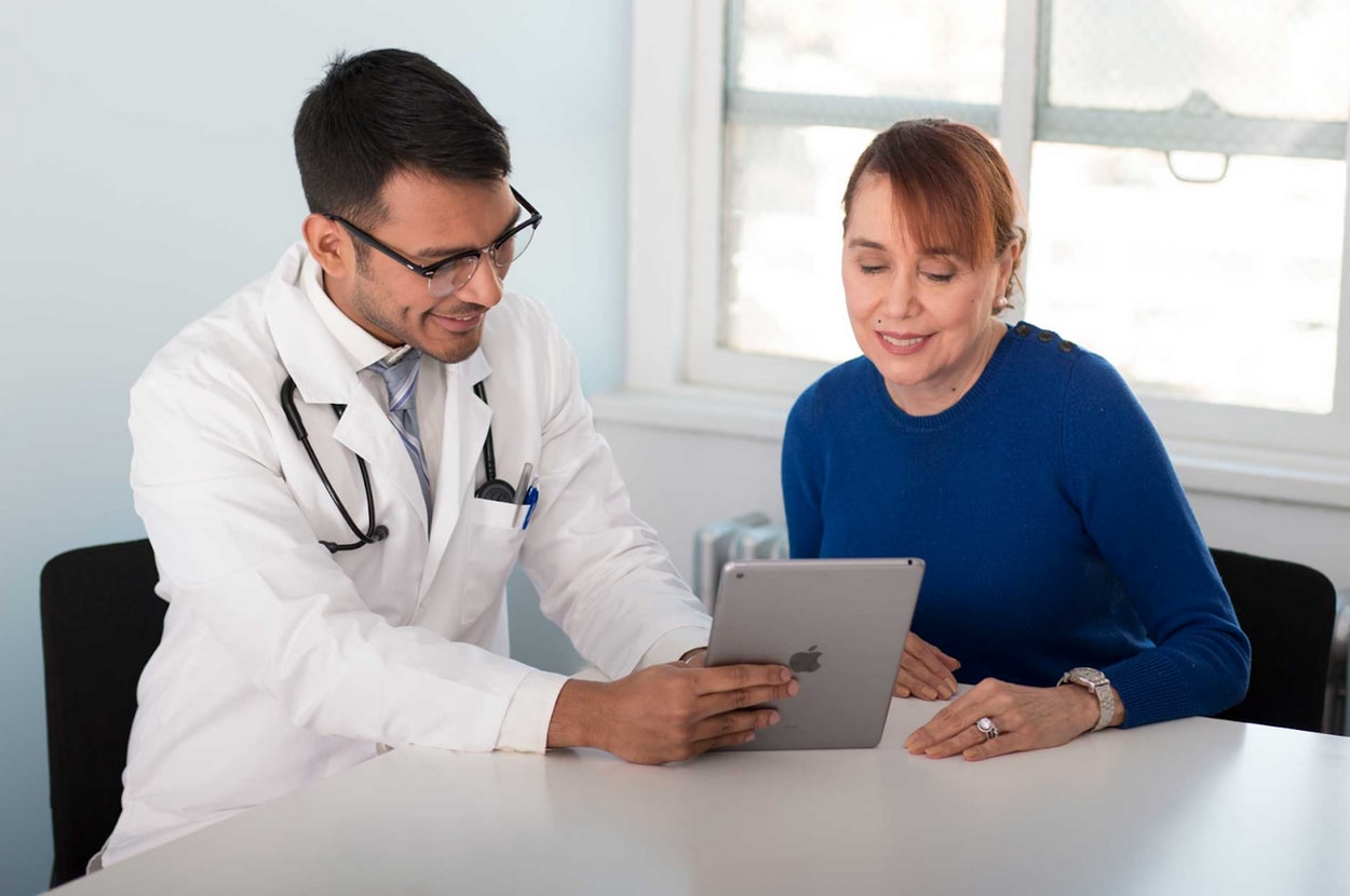 A doctor reviewing medications on a tablet with a patient