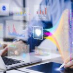 A pharmacist reviews graphs and charts using a computer and tablet