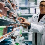 Two pharmacists looking at a shelf of prescriptions
