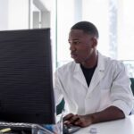 A young pharmacist at a computer learning how to use new pharmacy software