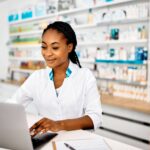 A pharmacist reviewing a detailed patient profile in pharmacy software at an independent pharmacy